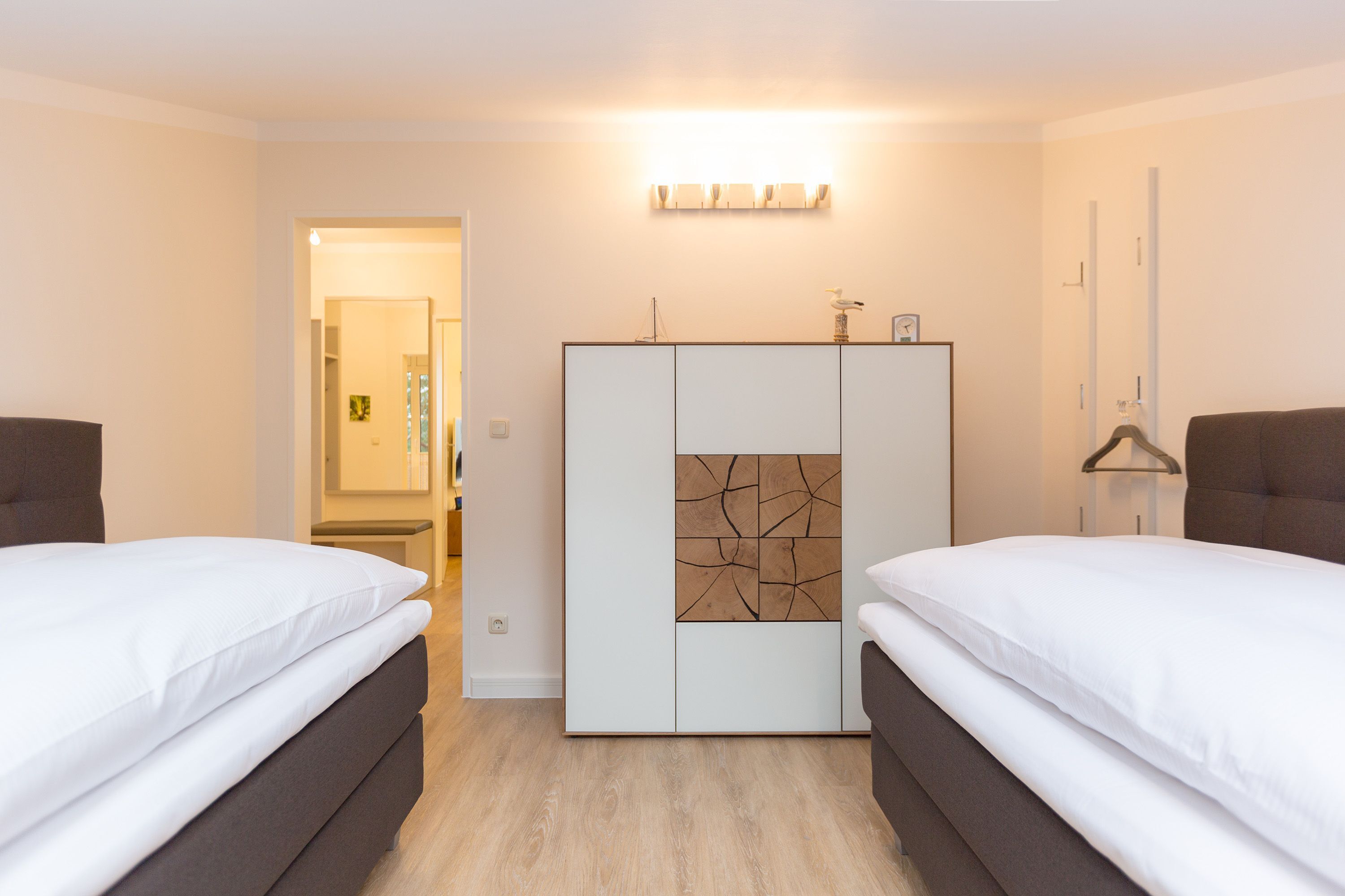 Une chambre d’hôtel avec deux lits, une armoire, un miroir et un luminaire.