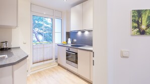 A modern kitchen with a built-in oven, a sink, and a window overlooking a balcony. - Haus am Schloonsee, app. B7 (Heringsdorf)