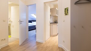 A modern hotel room with a wooden floor, a bed, a kitchenette, and a bathroom. - Haus am Schloonsee, app. B7 (Heringsdorf)