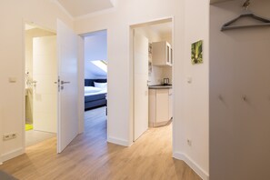 Una habitación de hotel moderna con suelo de madera, una cama, kitchenette y un baño.