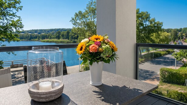 Un balcone con un tavolo, un vaso di fiori e un portacandele.