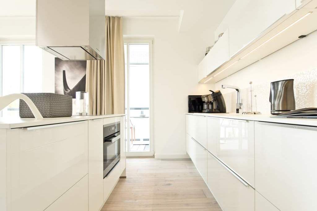 Eine moderne Küche mit weißen Schränken, einem Backofen und einer Kaffeemaschine.