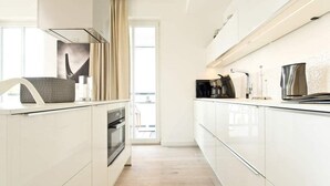 Una cucina moderna con mobili bianchi, forno integrato e macchina da caffè.