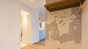 Ein Flur mit Holzboden, einer Europakarte an der Wand und einer Tür zu einem weiteren Raum.