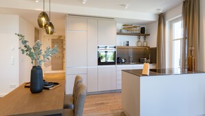 Una cocina moderna con una isla central, electrodomésticos integrados y un comedor con una mesa y sillas de madera.