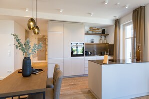 A modern kitchen with a central island, built-in appliances, and a dining area with a wooden table and chairs.