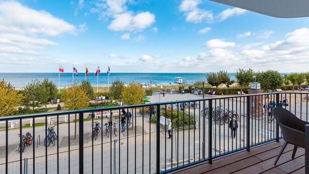 Un balcón con vistas al mar, un estacionamiento con bicicletas y una torre del reloj.