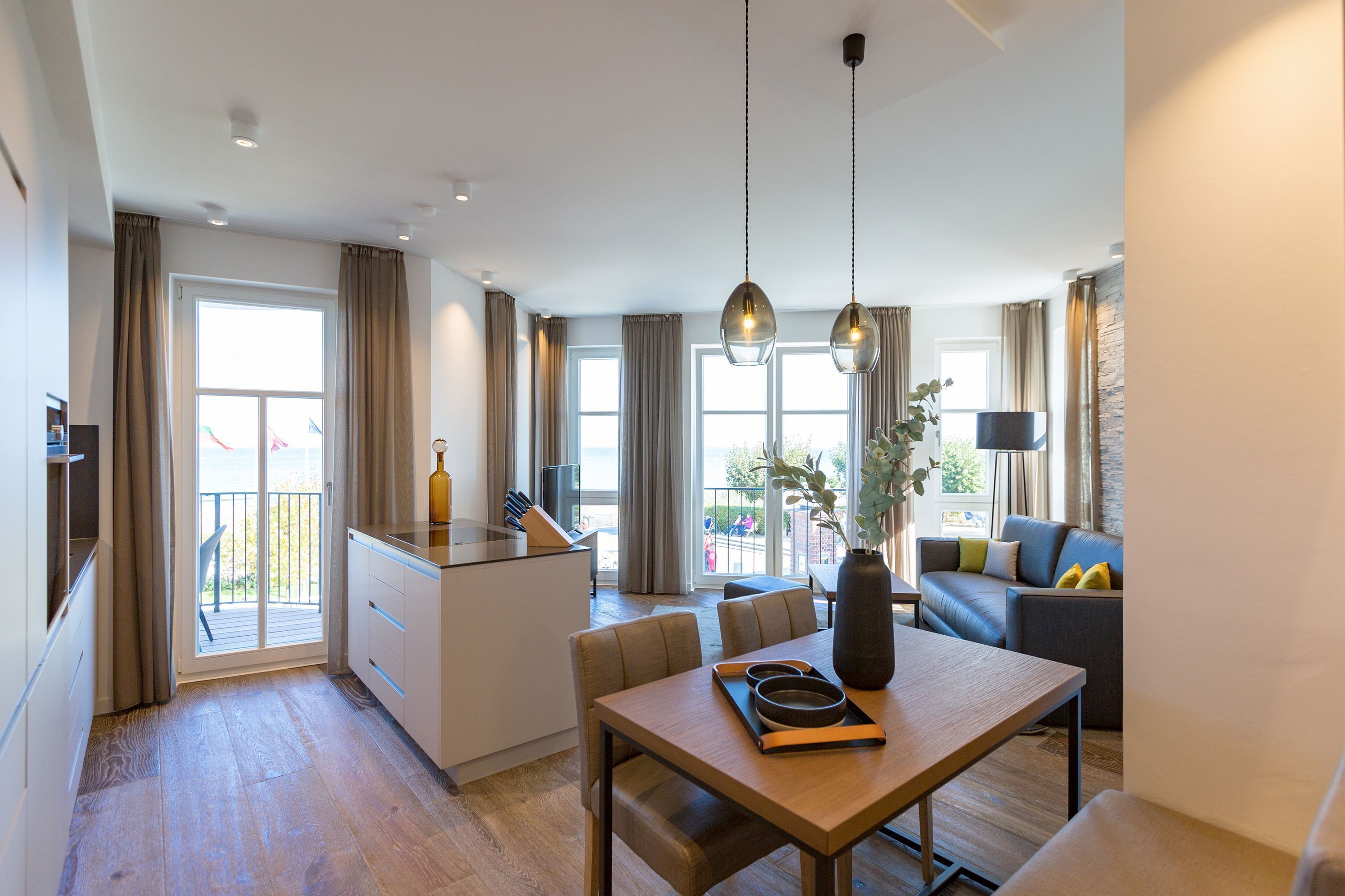 A modern living room with a dining table, sofa, and kitchen area.