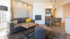 Una sala de estar moderna con un sofá gris, una mesa de centro de madera y una zona de comedor con una mesa y sillas.