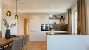 Una cocina moderna con armarios blancos, horno empotrado y una isla central.