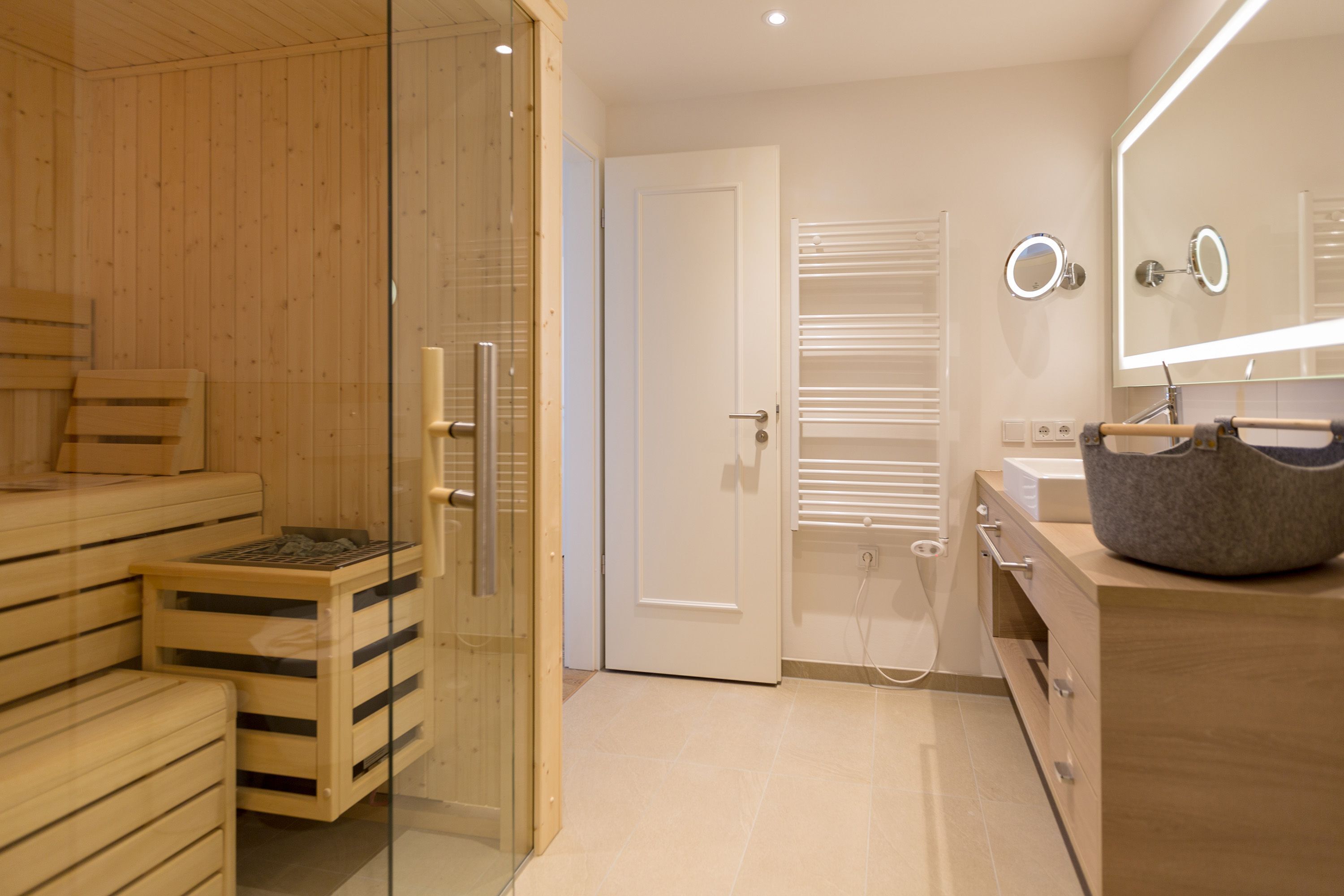 A modern bathroom with a sauna, a glass shower enclosure, and a vanity with a mirror.