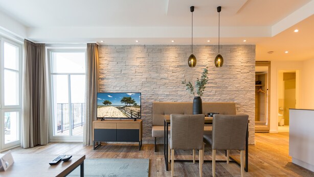 Un salon moderne avec un mur en pierre, un coin repas et une vue sur l’extérieur.