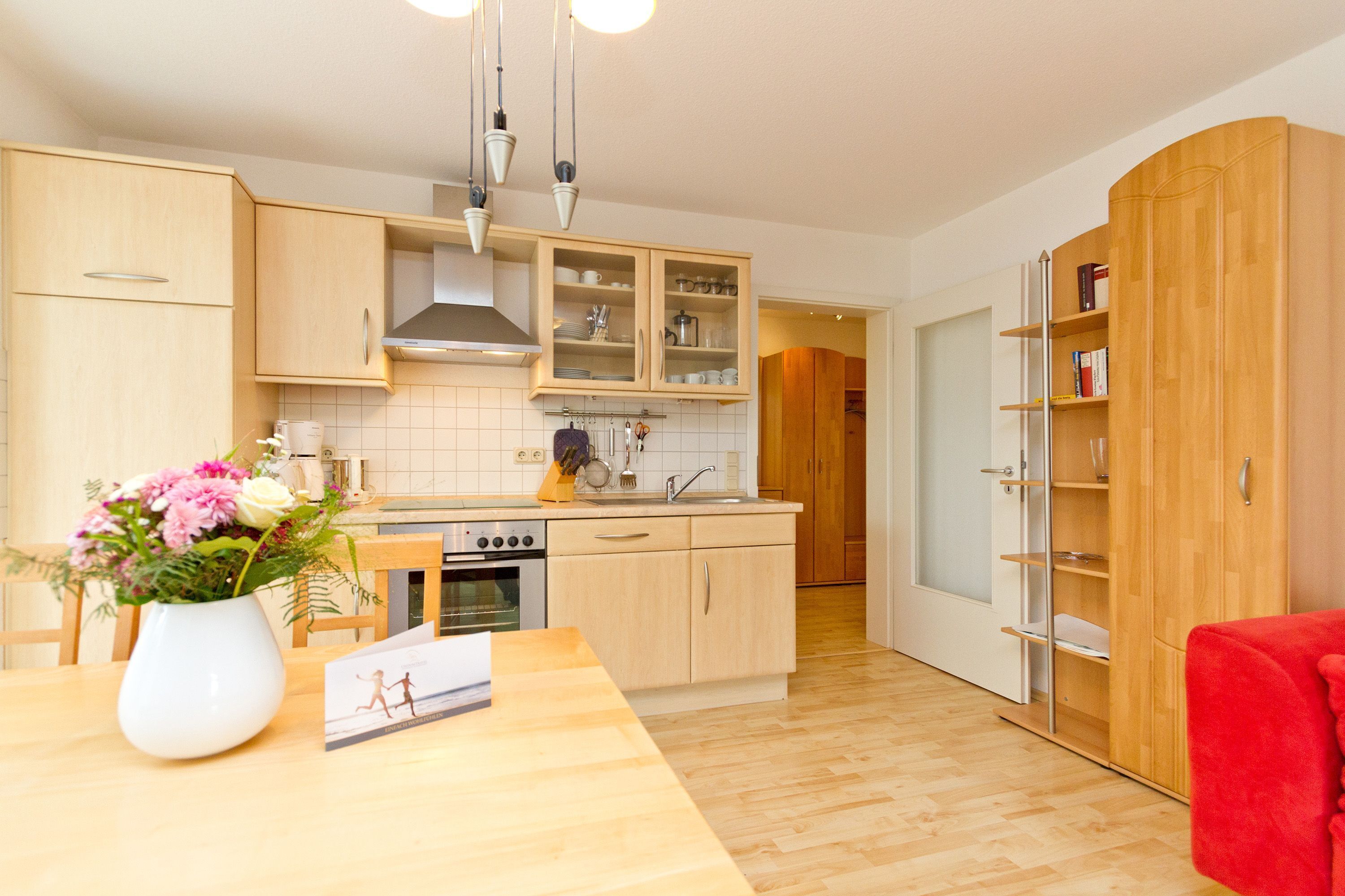 Eine moderne Küche mit Holzschränken, einem eingebauten Backofen und einem Essbereich mit Tisch und Stühlen.