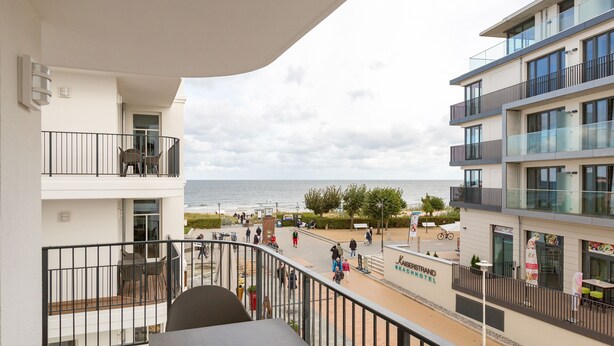Un balcón con vista a la playa y un edificio de hotel.