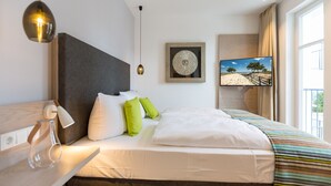 Habitación de hotel moderna con una cama grande, un televisor de pantalla plana, un adorno de pared y vistas al exterior.