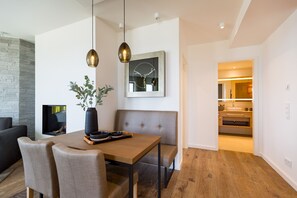 Un espace repas moderne avec une table en bois, deux chaises, un banc et une suspension.