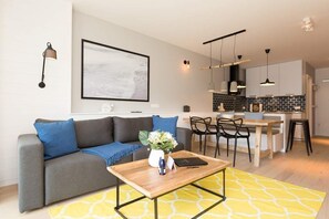 Uma sala de estar moderna com sofá, mesa de centro e área de jantar com cadeiras e mesa.