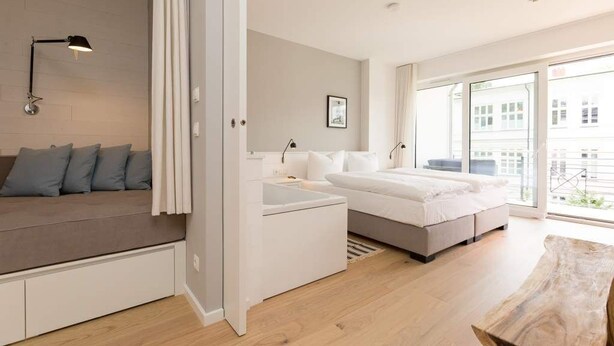 Una camera da letto moderna con un divano, due letti, una scrivania e un'ampia finestra.