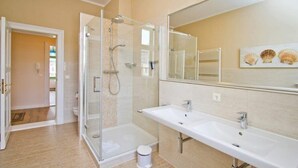 A bathroom with a glass-enclosed shower, two sinks, a large mirror, and a toilet. - Villa on the Baltic Sea beach, App. 5 (Heringsdorf)
