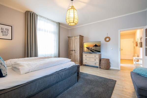 A bedroom with a bed, a dresser, a wardrobe, and a television.