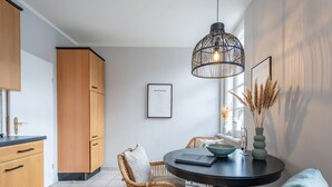 Una cocina moderna con armarios de madera, una mesa de comedor con sillas y una lámpara colgante.