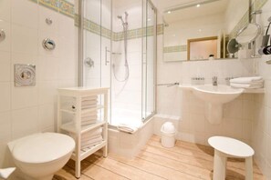 A modern bathroom with a glass-enclosed shower, a white sink, and a toilet.