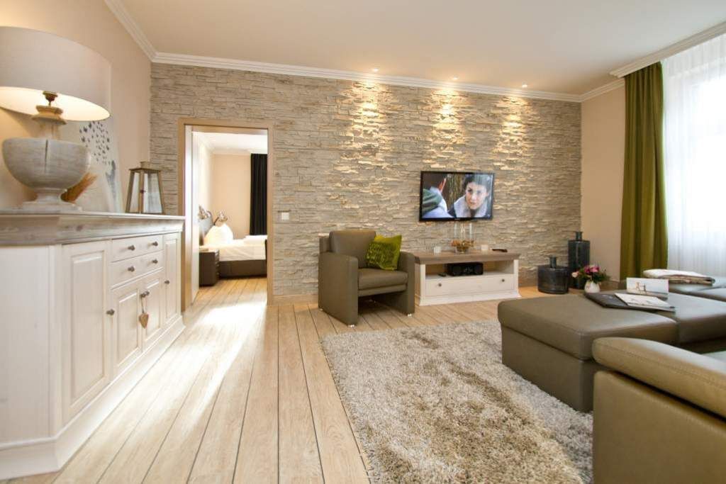 Un salon moderne avec un mur d’accent en pierre, un téléviseur à écran plat et un coin salon confortable.