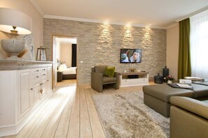 A modern living room with a stone accent wall, a flat-screen TV, and a cozy seating area.