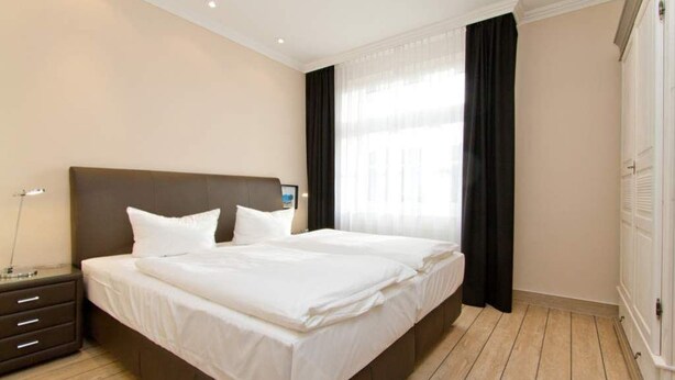 A hotel room with a large bed, a bedside table, and a wardrobe.