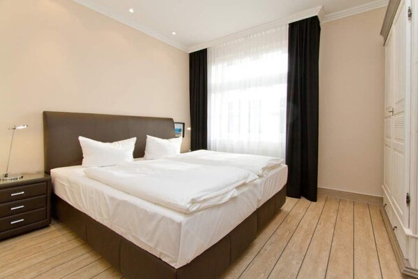 A hotel room with a large bed, a bedside table, and a wardrobe.