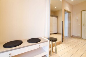 A room with a white vanity, two black circular objects on it, a small stool, and a wooden floor.