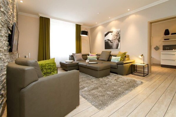 A modern living room with a sectional sofa, a small side table, and a large window with curtains.