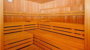 A wooden sauna with benches and a control panel on the wall.