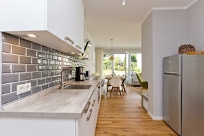 Une cuisine moderne avec un dosseret de carrelage gris, des appareils électroménagers en acier inoxydable et un plancher en bois.