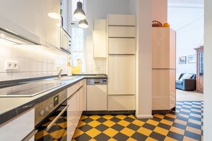 Uma cozinha moderna com armários brancos, bancada preta e piso xadrez.