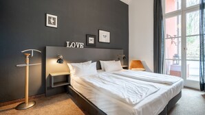 Et hotelværelse med en stor seng, et natbord, en lampe, en billedramme og ordet 'LOVE' på væggen.
