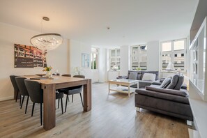 Un salon moderne avec une table à manger, un canapé et de grandes fenêtres.