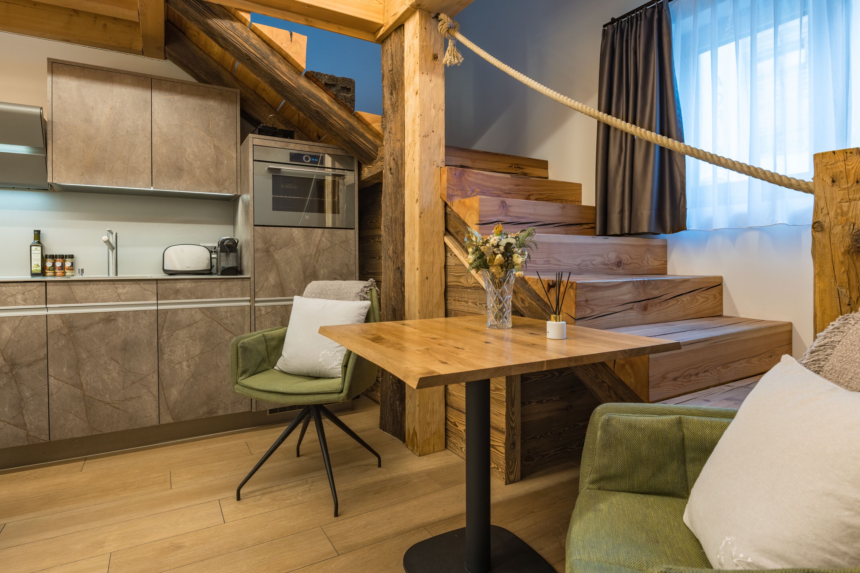 A modern kitchen with wooden cabinets, a built-in oven, and a dining area with a wooden table and green chairs.