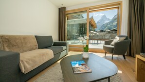 A modern living room with a sofa, armchair, and coffee table. A magazine is on the table. - Luxury Residence Colosseo Zermatt (Zermatt)