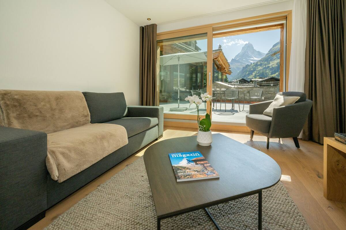 A modern living room with a sofa, armchair, and coffee table. A magazine is on the table.