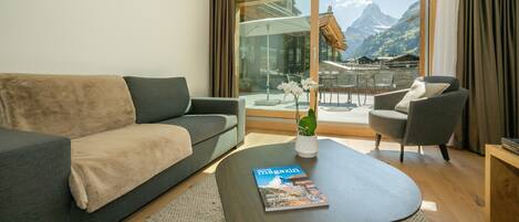 Una sala de estar moderna con un sofá, un sillón y una mesa de centro. Hay una revista sobre la mesa.