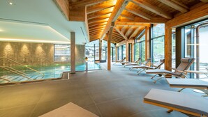 A spa area with a pool, sun loungers, and large windows offering views of the outdoors. - Luxury Residence Colosseo Zermatt (Zermatt)