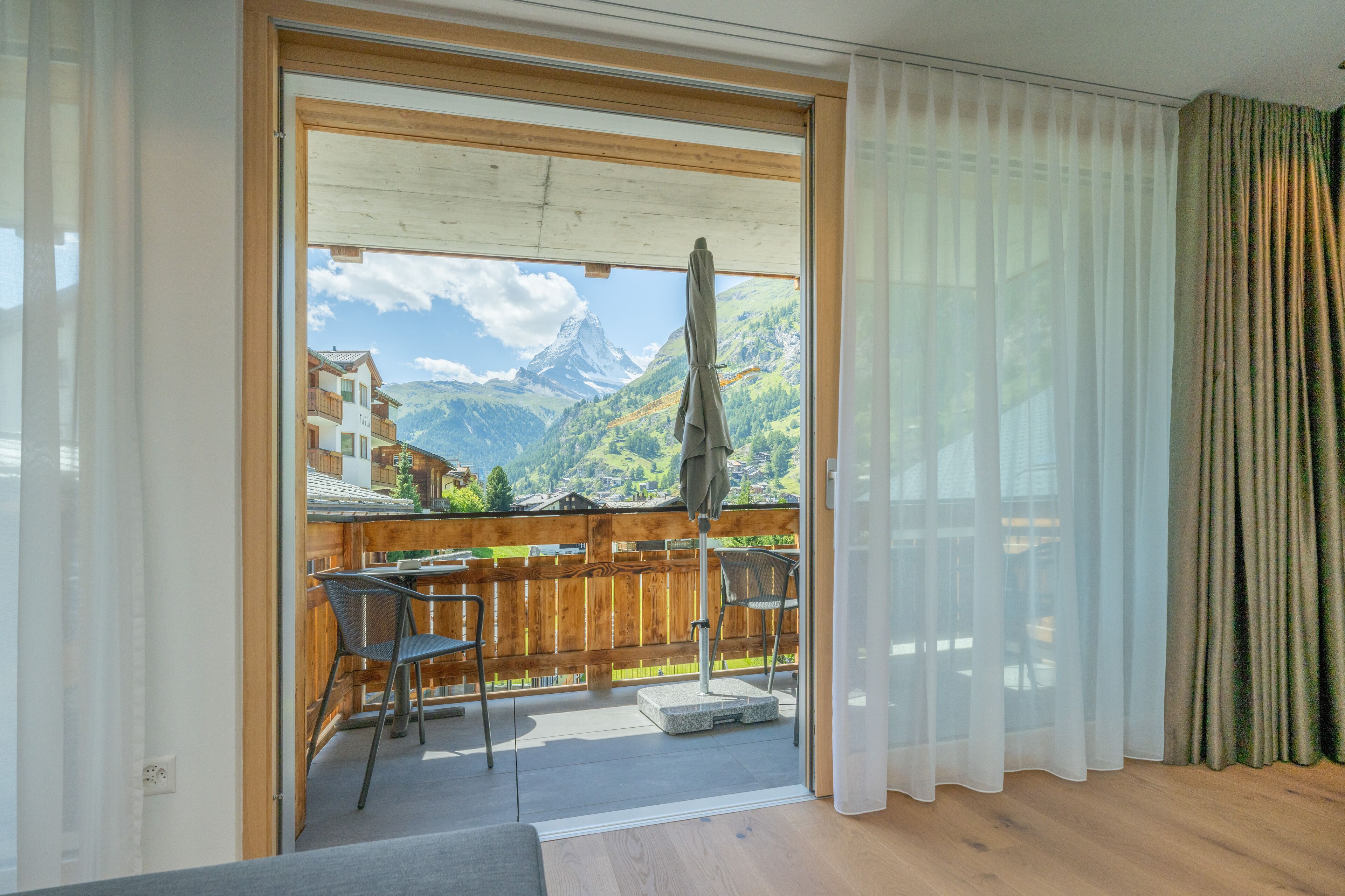Un balcon avec une balustrade en bois, deux chaises et une table.