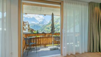 A balcony with a wooden fence, two chairs, and a table.