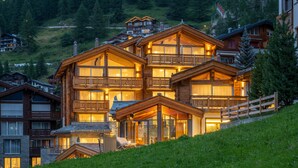 A multi-story wooden lodge with balconies, large windows, and a stone facade. - Luxury Residence Colosseo Zermatt (Zermatt)