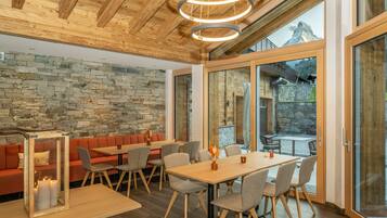 Un comedor moderno con pared de piedra, techo de madera y ventanas grandes que ofrecen vistas a la montaña.