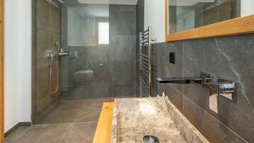 A modern bathroom with a glass-enclosed shower, a wooden vanity, and a large mirror.