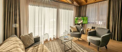 Uma sala de estar moderna com um sofá, poltronas, uma mesa de centro e uma televisão.