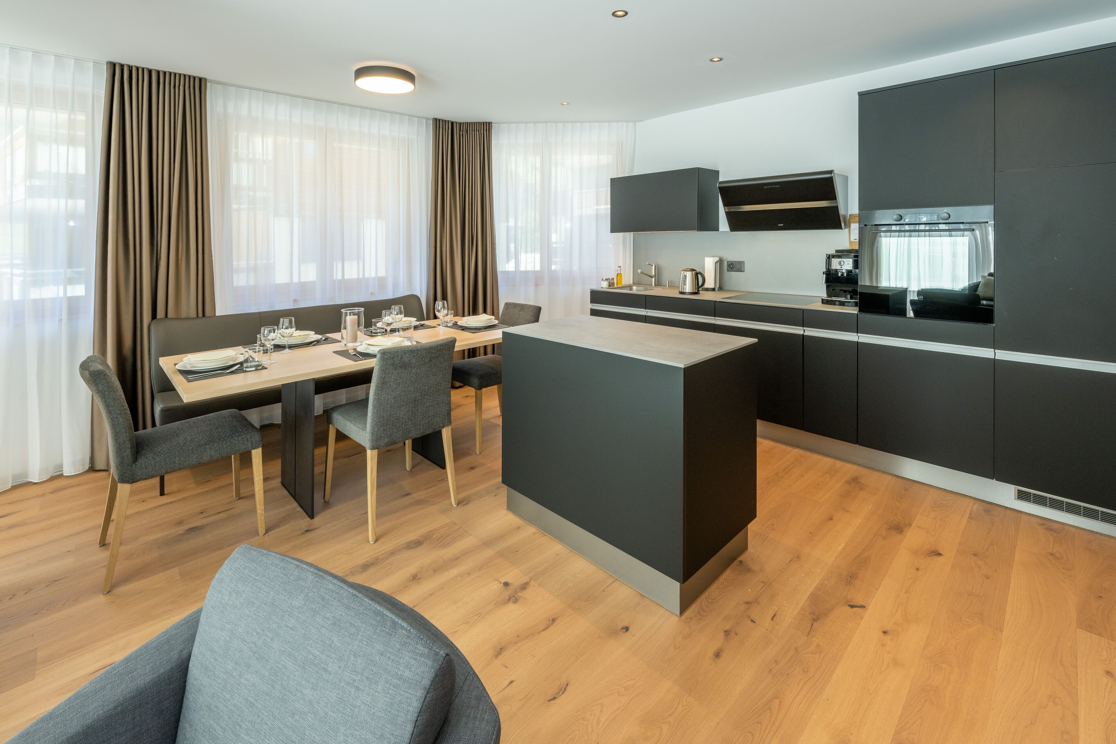 Quarto de hotel moderno com área de refeições, cozinha e espaço para sentar.