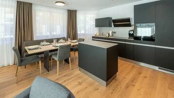 Quarto de hotel moderno com área de refeições, cozinha e espaço para sentar.
